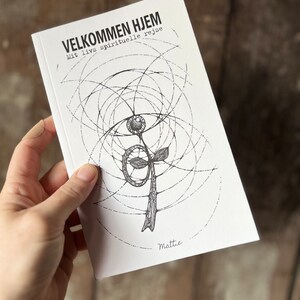 Könnte beinhalten: Ein weißes Buch mit dem Titel "Velkommen Hjem" und dem Untertitel "Mit livs spirituelle rejse". Das Buch zeigt eine Schwarzweißillustration einer Blume mit einem Kreis darum.