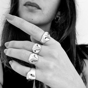 May include: A hand wearing four silver rings with black accents. The rings are shaped like owls with their eyes set with black stones.