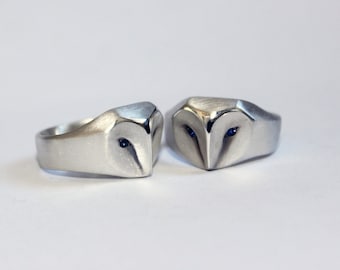 May include: Two silver rings with a sculpted owl design. Each owl has blue eyes.