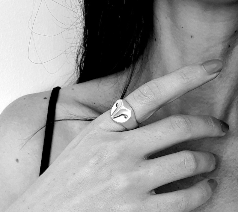 May include: A silver ring with an owl design. The owl's eyes are set with small, clear stones.