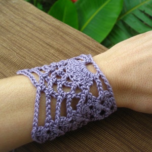 May include: A lavender crocheted bracelet with a delicate floral pattern.