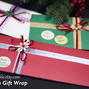 May include: Three gift-wrapped parcels with red, green and white paper. Each parcel has a different ribbon and a small flower embellishment. The parcels are decorated with personalised gift tags.
