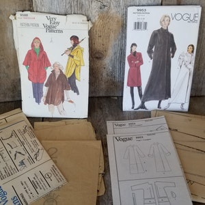 May include: Three vintage Vogue sewing patterns for coats. The patterns are for sizes 8-18. The patterns are on a wooden surface.