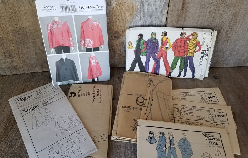 May include: A collection of vintage Vogue sewing patterns, including patterns for jackets, tops, and pants. The patterns are in various colors and styles, and some have illustrations of the finished garments.