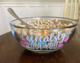 May include: A glass bowl filled with cereal and marshmallows. The bowl has a white inscription that reads "I cereally love you" with pink hearts.