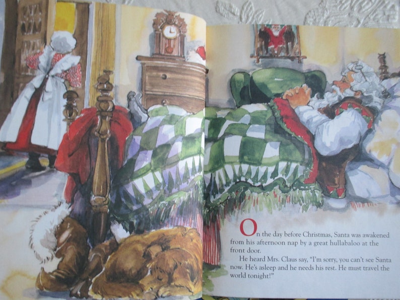 May include: A watercolour illustration of Father Christmas sleeping in a bed with a green and white checked blanket. The text reads, "On the day before Christmas, Santa was awakened from his afternoon nap by a great hullabaloo at the front door. He heard Mrs. Claus say, 'I'm sorry, you can't see Santa now. He's asleep and he needs his rest. He must travel the world tonight!'"