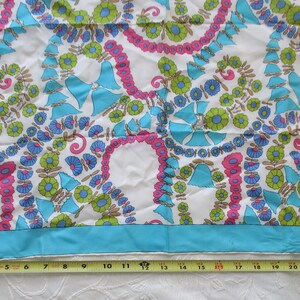 May include: A white silk scarf with a blue, green and pink floral pattern. The scarf has a turquoise border.