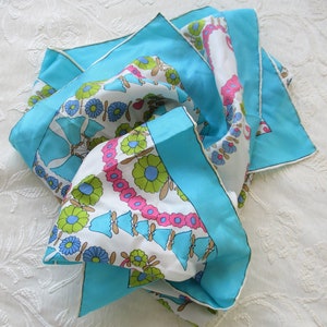 May include: A turquoise blue silk scarf with a white background and a floral pattern in pink, green, and blue.