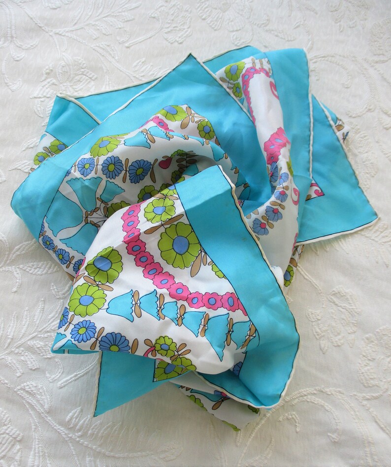 May include: A turquoise blue silk scarf with a white background and a floral pattern in pink, green, and blue.