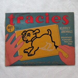May include: A blue and yellow tracing pad with a picture of a puppy on the front. The pad is labelled "Tracies" and "Kuddly Animals". The text "Set 1" is in a circle on the left side of the pad. The text "Drawings Alphabet Tracing Pad" is on the right side of the pad. The text "teaches them at play" is at the bottom of the pad.