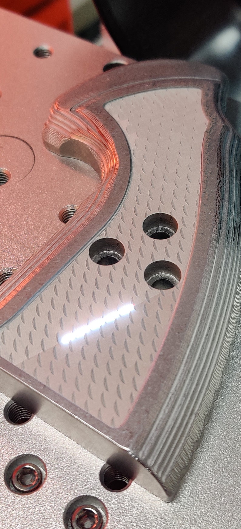 K&ouml;nnte beinhalten: Ein silberner Metallgriff f&uuml;r eine Pistole mit einer strukturierten Oberfl&auml;che und drei L&ouml;chern. Der Griff hat ein gerilltes Design an der Seite.