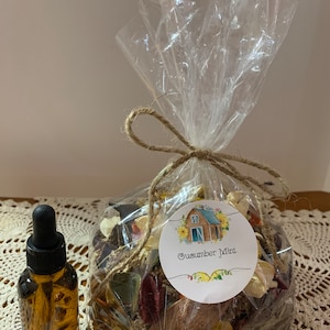 May include: A clear plastic bag filled with potpourri, tied with twine and a label that reads "Cucumber Mint". A small brown glass bottle with a dropper is next to the bag.
