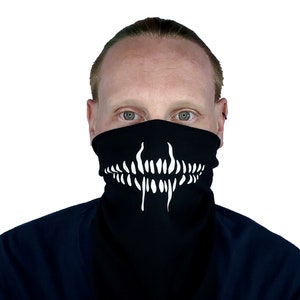 May include: A black face mask with a white skull and teeth design. The mask is worn by a person with blonde hair.