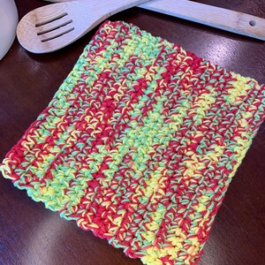 May include: A crocheted kitchen dishcloth in red, yellow, and green. The dishcloth is made with a textured stitch pattern.