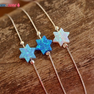 Puede incluir: Tres pulseras de cadena de plata con dijes de estrella de David de ópalo. Las estrellas son en tonos de azul y blanco.
