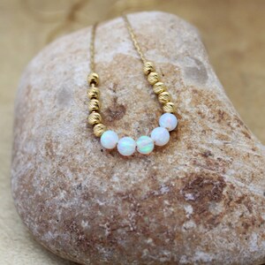May include: A gold chain necklace with small gold beads and white opal beads.
