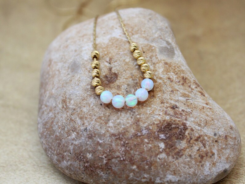 May include: A gold chain necklace with small gold beads and white opal beads.
