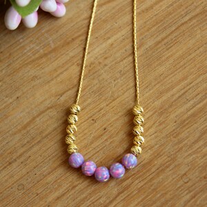 May include: A gold chain necklace with a row of small gold beads and a center row of five iridescent purple opal beads.