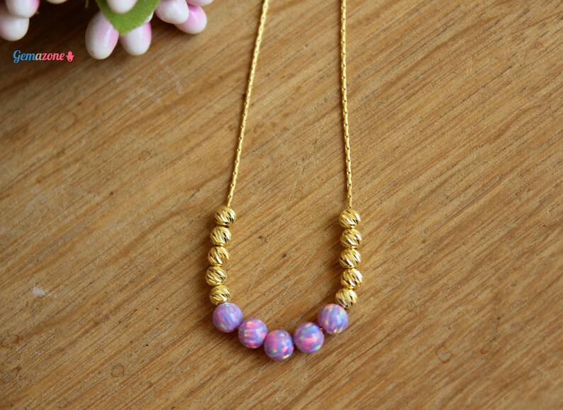 May include: A gold chain necklace with a row of small gold beads and a center row of five iridescent purple opal beads.