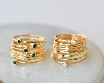 May include: A set of gold rings with green and white gemstones. The rings are stacked on top of each other and have a hammered texture.