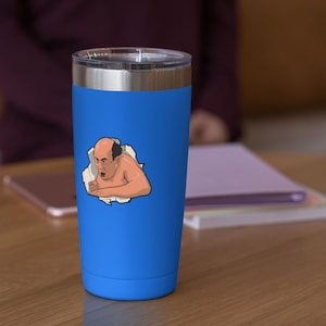 Peut inclure: Un gobelet isotherme en acier inoxydable bleu avec un autocollant blanc repr&eacute;sentant un homme de dessin anim&eacute; chauve, avec une expression surprise, qui sort d'un morceau de papier d&eacute;chir&eacute;.