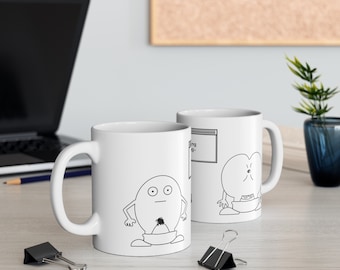 May include: Two white ceramic mugs with black line drawings of cartoon characters. One mug features a character with a round head, two eyes, and a single hair on its chin. The other mug features a character with a round head, two eyes, and a mouth.