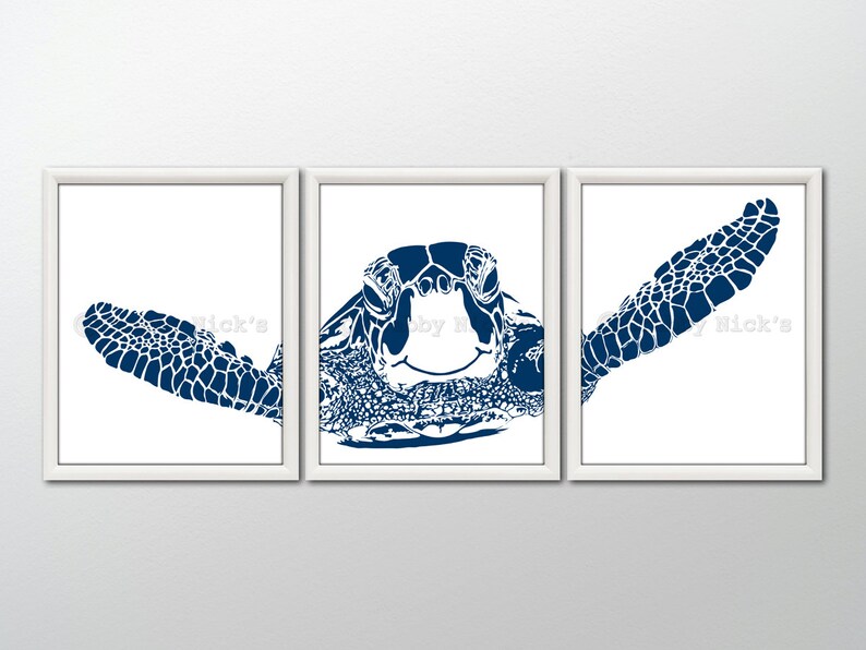 May include: A set of three blue and white silhouette prints of a sea turtle. The prints are framed in white frames and are arranged in a row on a white wall.