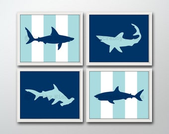 May include: Set of four blue and white framed prints featuring silhouette images of sharks. The prints have a nautical theme and are perfect for a child's room or nursery.
