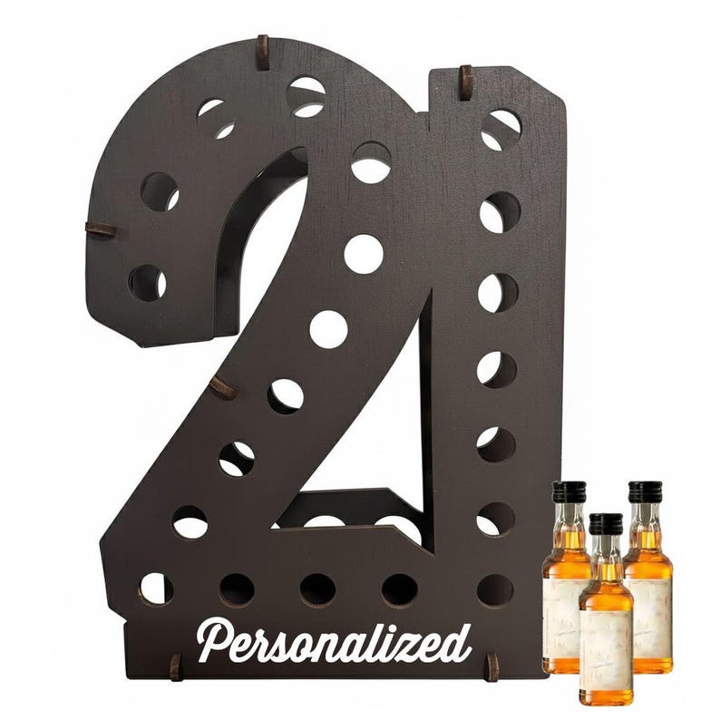 May include: A dark brown wooden display stand shaped like the number 21, featuring multiple circular cutouts for holding small bottles. The word Personalized is printed in white script at the base, accompanied by three small glass liquor bottles.