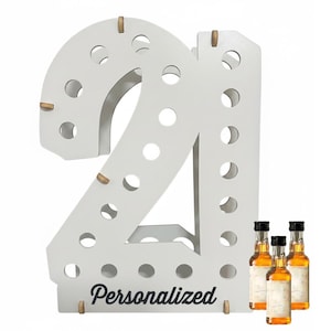 May include: A white wooden display stand shaped like the number 21, featuring multiple circular cutouts for holding small bottles. The base of the stand displays the word Personalized in black script. Three small amber-colored glass bottles are included.