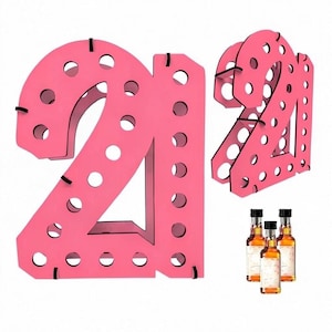 May include: A bright pink wooden display stand shaped like the number 21, featuring multiple circular cutouts designed to hold small bottles. The structure is shown from a front-facing view and an angled perspective, accompanied by three miniature glass bottles.