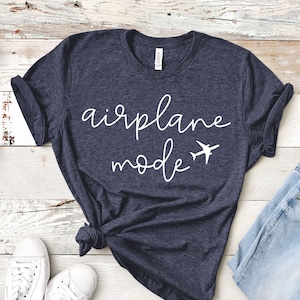 May include: A dark blue t-shirt with the text "airplane mode" in white cursive lettering and a small airplane graphic.