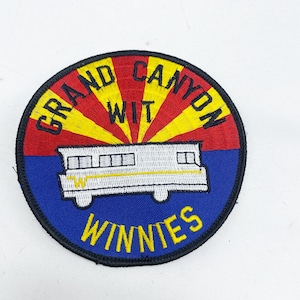 May include: A round, blue, yellow, and red embroidered patch with the text "Grand Canyon Wit Winneies" and a white camper van with yellow accents.