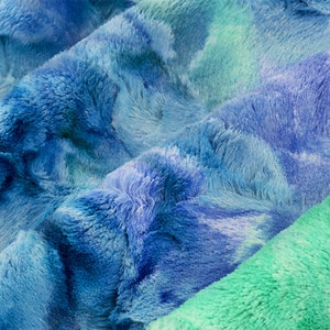 May include: Close-up of a soft, blue and green tie-dye fabric with a fuzzy texture.