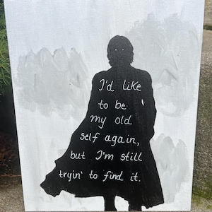 May include: A rectangular canvas painting featuring a black silhouette of a person wearing a long coat against a light gray, brush-stroked background. The text "I'd like to be my old self again, but I'm still tryin' to find it." is written in white.