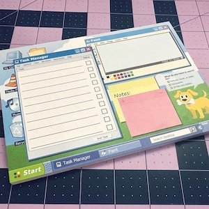 May include: A notepad designed to resemble a computer desktop interface. The notepad features a "Task Manager" window, a "Paint" window, and a "Notes" section with a pink sticky note. A cartoon dog is also visible. The notepad is on a pink and blue checkered surface.