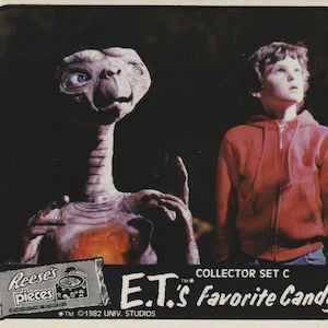 Puede incluir: Una tarjeta coleccionable vintage con E.T. el Extraterrestre y un niño con una sudadera roja. La tarjeta incluye el texto "E.T.'s Favorite Candy" y un logotipo de Reese's Pieces. Colección C, número 1.
