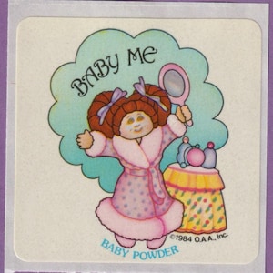 Könnte beinhalten: Vintage-Aufkleber mit einer Zeichentrickfigur in einem rosa Bademantel mit lila Punkten, die einen Spiegel hält. Der Text "BABY ME" steht über der Figur und "BABY POWDER" darunter. Rechts ist ein kleiner Tisch.