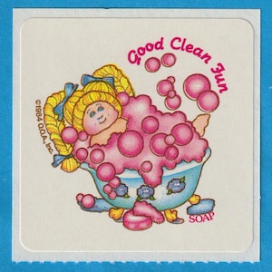 May include: A sticker featuring a cartoon girl taking a bath in a tub full of pink bubbles. The text "Good Clean Fun" is written in a circle around the girl. The text "SOAP" is written below the tub.