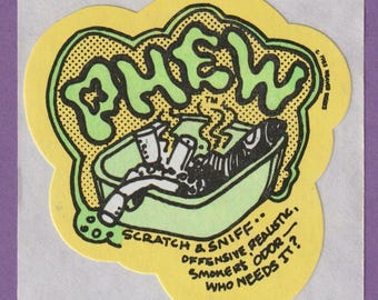 May include: A yellow and green sticker with the word "PHEW" in a cartoon font. The sticker has a scratch and sniff feature and says "Offensive, Realistic, Smokers Odor - Who Needs It?"