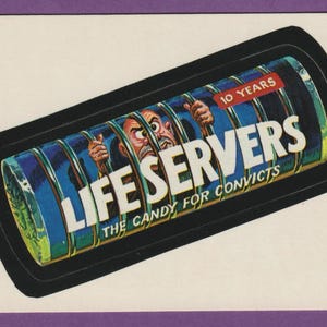 Peut inclure: Une carte à collectionner vintage avec une illustration de dessin animé d'un homme derrière des barreaux. La carte affiche le texte "LIFE SERVERS" en blanc, avec "THE CANDY FOR CONVICTS" en dessous. Le haut de la carte indique "10 YEARS".