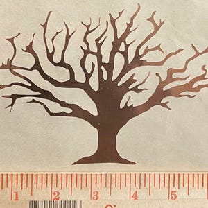 May include: A copper-colored silhouette of a bare tree with many branches. The tree is on a white background with a ruler underneath.