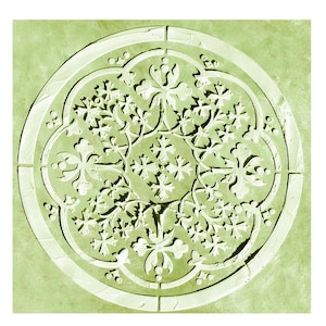 May include: A circular, light green stone carving with an intricate floral design. The design features a central arrangement of stylized flowers and leaves, surrounded by a decorative border. The carving is set against a light green background.