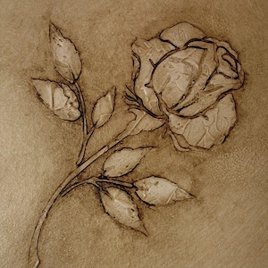 May include: A detailed, sepia-toned image of a rose and leaves, likely wood-burned or etched into a surface. The rose is in full bloom, with intricate detailing on the petals and leaves. The background has a textured appearance.
