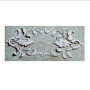 May include: A rectangular, off-white decorative panel featuring a symmetrical floral design. The raised relief pattern includes stylized leaves and curved stems, creating a textured, three-dimensional effect. The background has a mottled, neutral color.