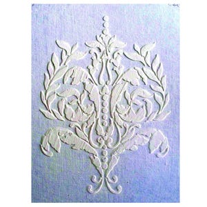 May include: A white, raised floral design against a light blue background. The symmetrical pattern features leaves, flowers, and a central vertical element with a series of circles. The design is likely for wall decor or a similar craft project.