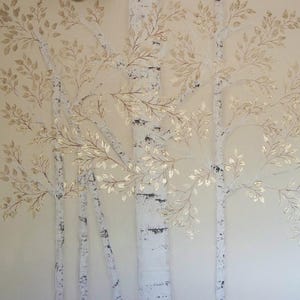 May include: A wall art piece featuring a stylized depiction of birch trees. The trees have white bark with black markings and are adorned with gold-colored leaves. The background is a soft, neutral tone, creating a serene and natural aesthetic.
