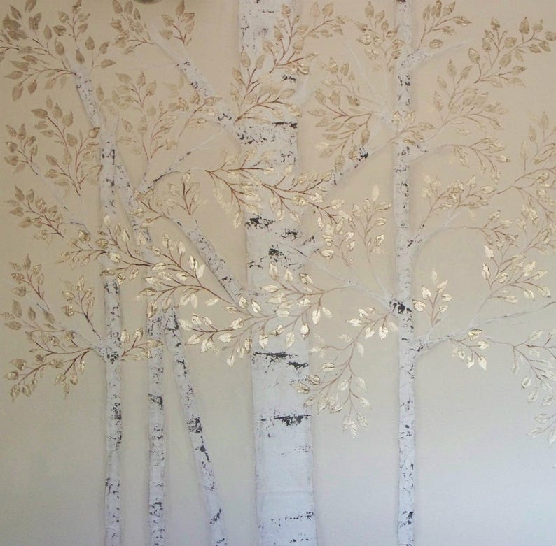 May include: A wall art piece featuring a stylized depiction of birch trees. The trees have white bark with black markings and are adorned with gold-colored leaves. The background is a soft, neutral tone, creating a serene and natural aesthetic.