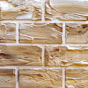 May include: Close-up of a brick wall with a textured surface. The bricks are rectangular and have a light brown color with darker brown and beige accents. The mortar between the bricks is white.