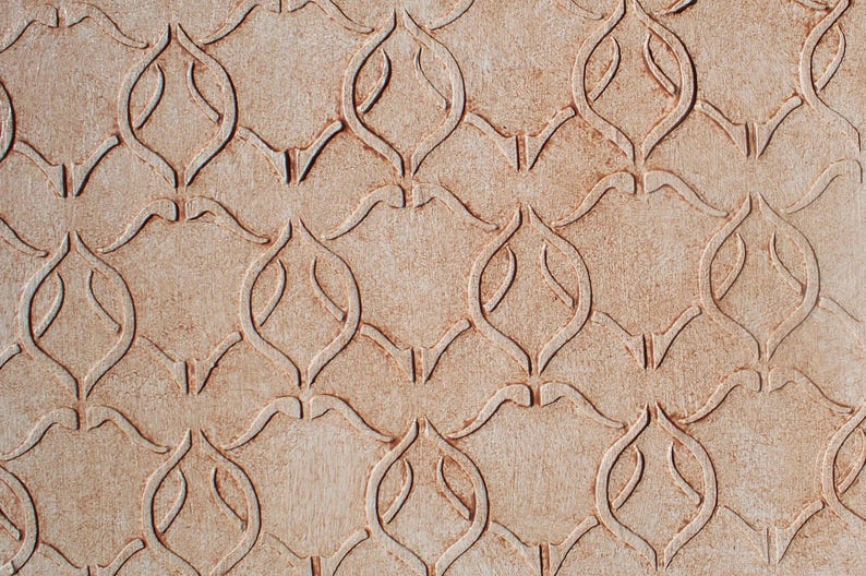 Puede incluir: Primer plano de una superficie beige texturizada con un patr&oacute;n repetitivo de formas florales o de hojas estilizadas e interconectadas. El dise&ntilde;o est&aacute; en relieve, creando un sutil efecto de relieve.